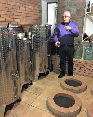 A Georgian man continues an 8000-year-old tradition in the wine cellar of his home. 'Quevre' are buried at his feet.